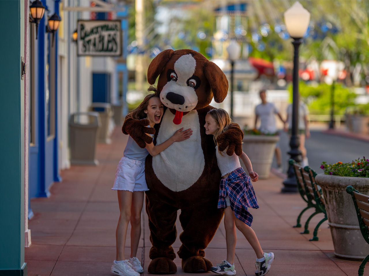 Two young girls with Adventureland's mascot, hugging